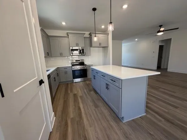 a large kitchen with stainless steel appliances a large counter top a sink a stove and a refrigerator