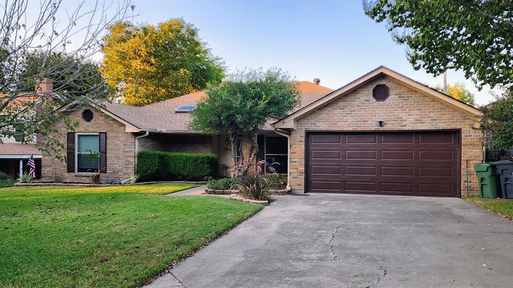 Ranch-style home featuring a front lawn, driveway, brick siding, and shingle roof.