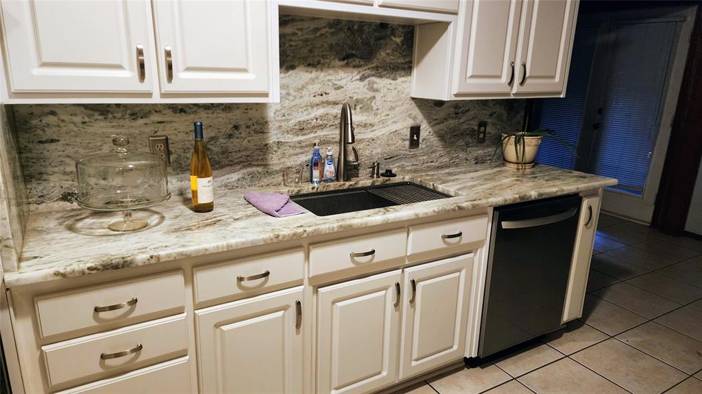 7505 Patsy Court Arlington, TX 76016 - Photo 15 of 38 Kitchen featuring black appliances, light tile patterned floors, a textured ceiling, a textured wall, dolomite countertops, and white cabinetry.