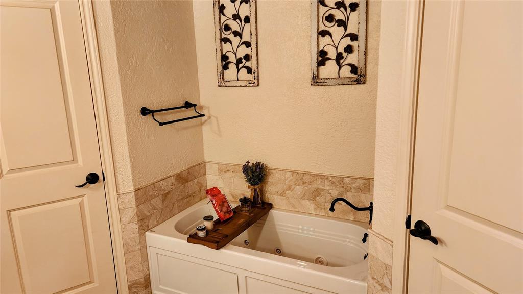 7505 Patsy Court Arlington, TX 76016 - Photo 20 of 38 Bathroom with a textured wall, a Jacuzzi jetted tub, tile walls, a stall shower, and a wainscoted wall.