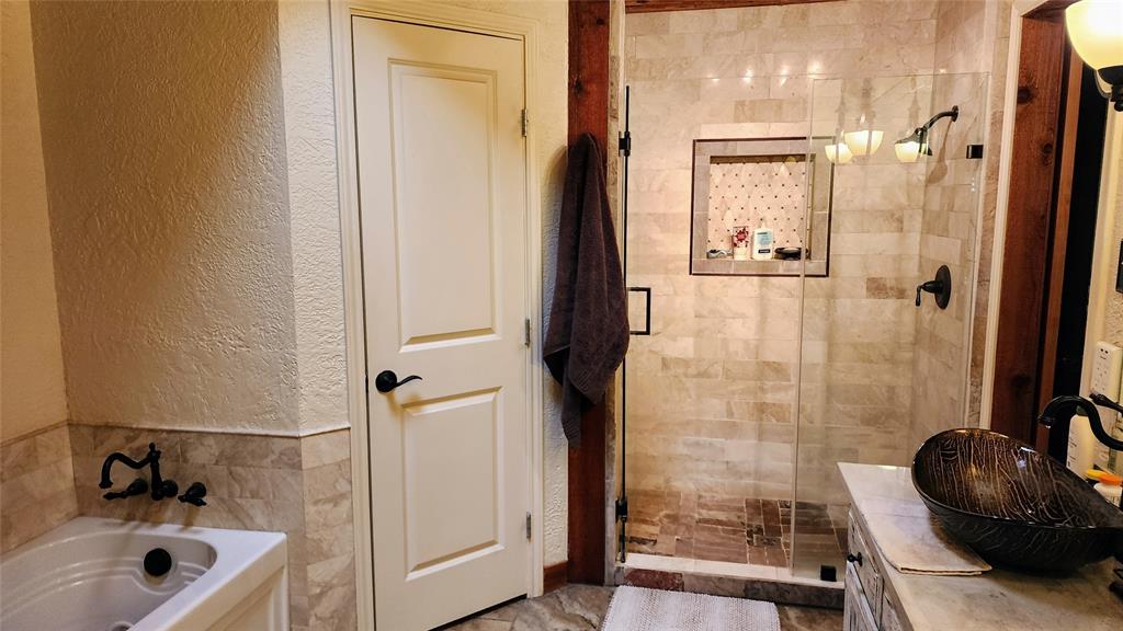 7505 Patsy Court Arlington, TX 76016 - Photo 22 of 38 Bathroom featuring a textured wall, a shower stall, tile walls, vanity, and a Jacuzzi jetted tub.