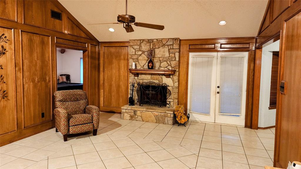 7505 Patsy Court Arlington, TX 76016 - Photo 3 of 38 Living room with lofted ceiling, light tile patterned floors, a ceiling fan, and picture frame paneling walls.