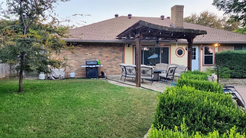 7505 Patsy Court Arlington, TX 76016 - Photo 31 of 38 Back of house with a patio, a pergola, roof with shingles, a lawn, and brick siding.