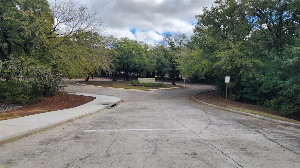 7505 Patsy Court Arlington, TX 76016 - Photo 38 of 38 Nearby Community Park with concrete road featuring curbs and view of wooded area.