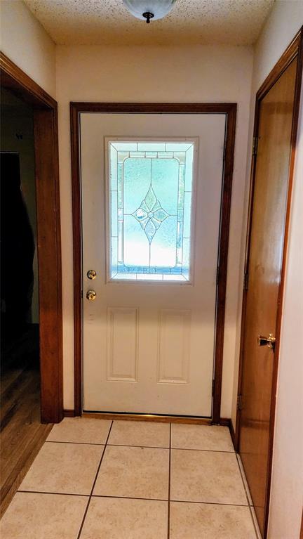 7505 Patsy Court Arlington, TX 76016 - Photo 5 of 38 Doorway featuring tile patterned flooring and a textured ceiling.