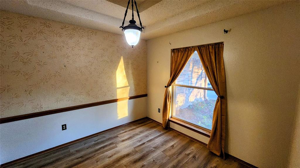 7505 Patsy Court Arlington, TX 76016 - Photo 10 of 38 Formal Dining Room with vinyl flooring, textured ceiling, wainscoted wall, and wallpapered walls.