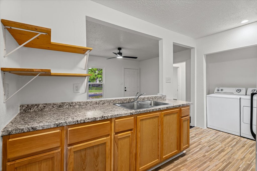 2206 Rountree Drive Austin, TX 78722 - Photo 6 of 16 Kitchen featuring a textured ceiling, open shelves, light countertops, light wood finished floors, and a ceiling fan