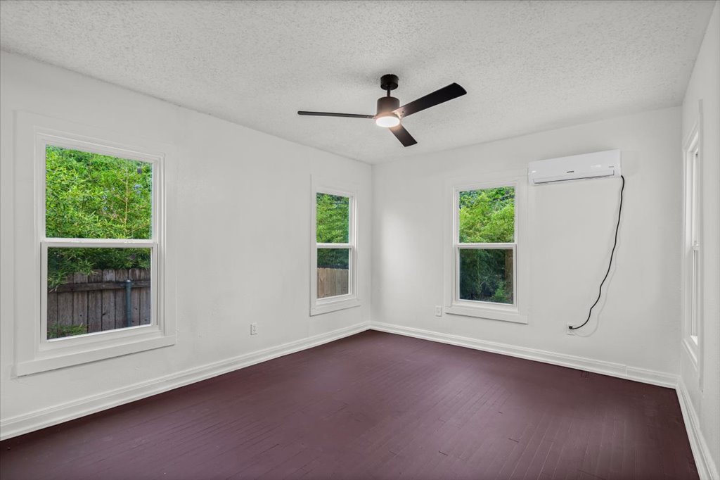 2206 Rountree Drive Austin, TX 78722 - Photo 8 of 16 Empty room featuring a textured ceiling, dark wood-style flooring, and ceiling fan