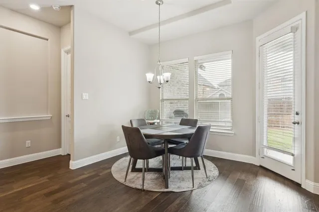 a kitchen with stainless steel appliances granite countertop a stove a sink a microwave a dining table and chairs with wooden floor