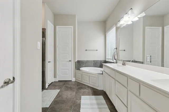 a spacious bathroom with a double vanity sink mirror and bathtub