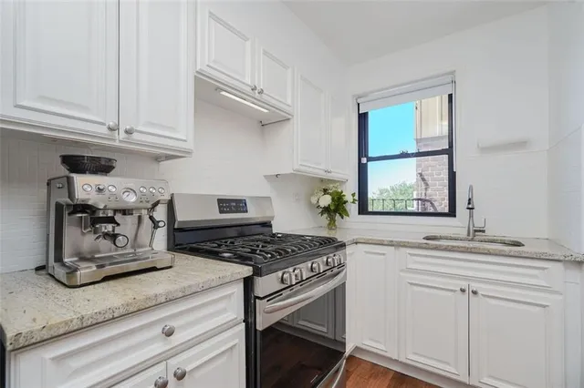 a kitchen with granite countertop stainless steel appliances stove a sink and cabinets