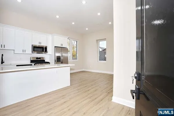 a kitchen with stainless steel appliances a sink a stove top oven a refrigerator and white cabinets