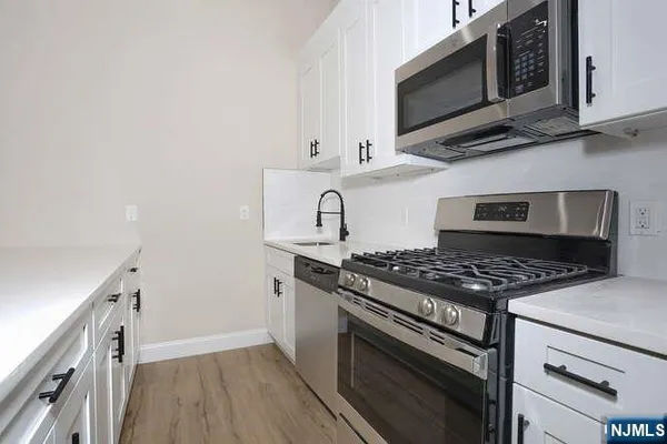 a kitchen with white cabinets and stainless steel appliances