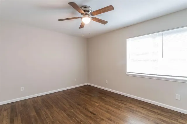 an empty room with a window and a fan