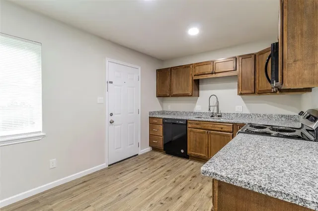 a kitchen with granite countertop a sink stove and cabinets
