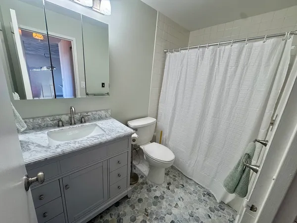 a bathroom with a granite countertop sink toilet and shower
