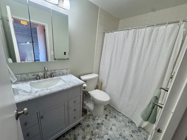 a bathroom with a granite countertop sink toilet and shower