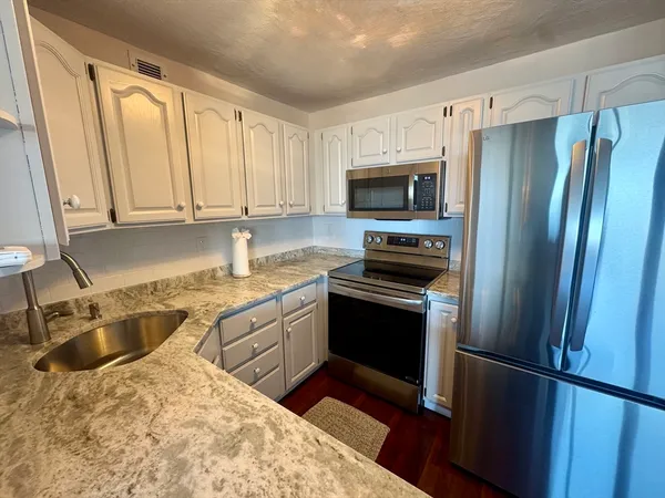 a kitchen with granite countertop a refrigerator sink and stove