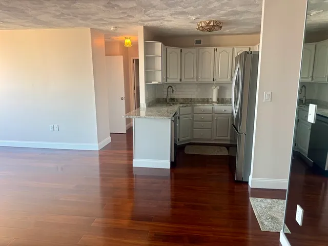 a kitchen with kitchen island wooden floor and refrigerator