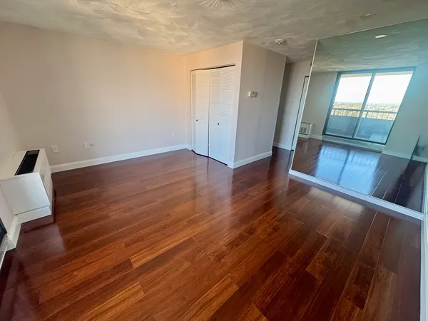 an empty room with wooden floor and windows