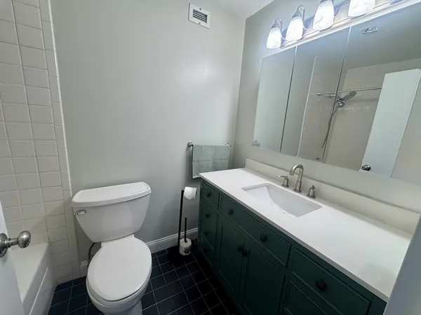 a bathroom with a granite countertop toilet sink and mirror