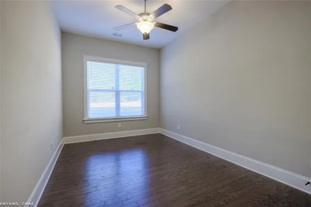 an empty room with wooden floor fan and windows