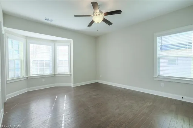 an empty room with wooden floor and a ceiling fan