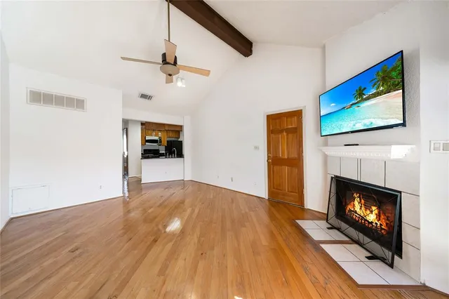 a view of an empty room with wooden floor fireplace and a window