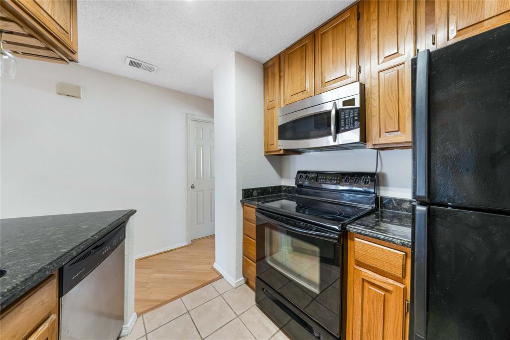 13217 Emily Road, Unit 3209 Dallas, TX 75240 - Photo 7 of 26 a kitchen with stainless steel appliances granite countertop a stove and a microwave