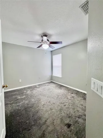 a view of an empty room with a chandelier fan
