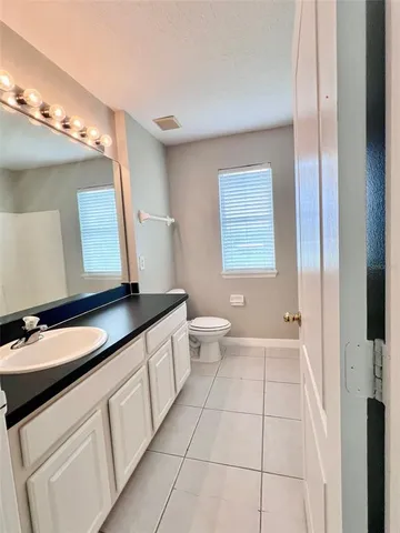a bathroom with a granite countertop sink a toilet a mirror a vanity and shower