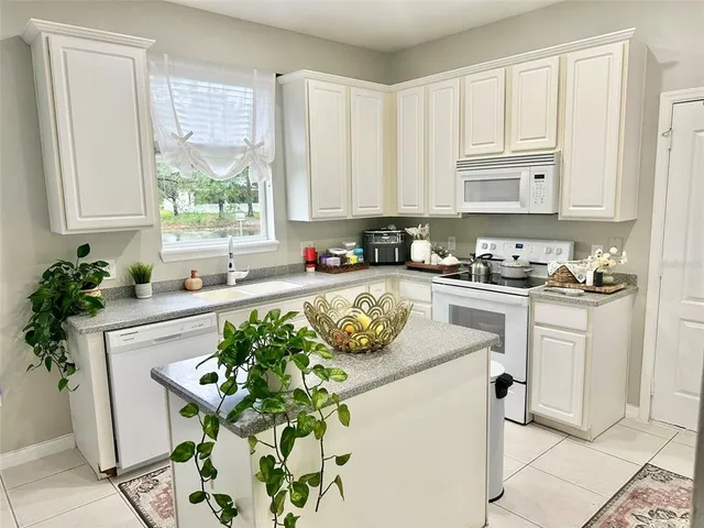 a white kitchen with a stove a sink and white cabinets
