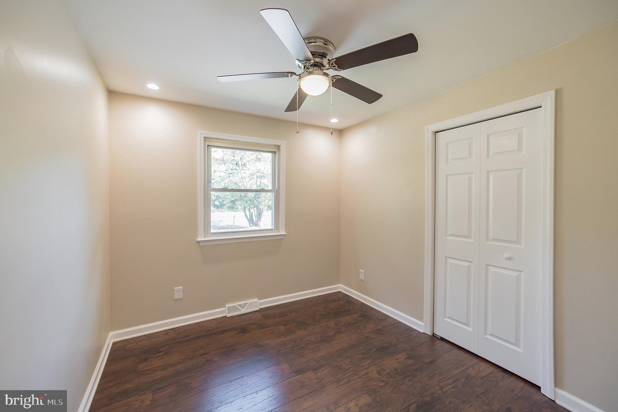 312 Fenwick Road Pilesgrove, NJ 08098 - Photo 14 of 40 an empty room with wooden floor ceiling fan and windows