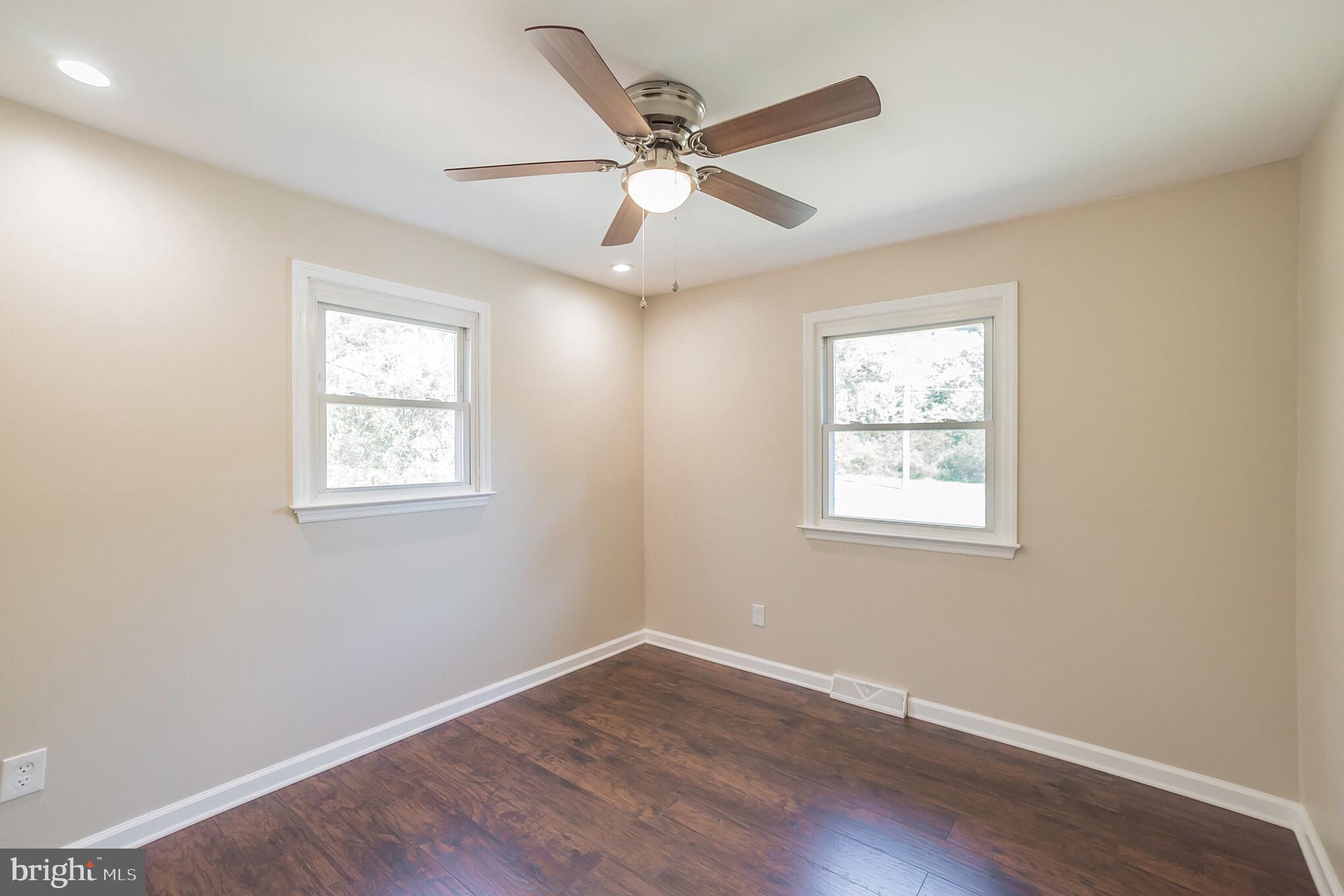 312 Fenwick Road Pilesgrove, NJ 08098 - Photo 17 of 40 an empty room with wooden floor ceiling fan and windows