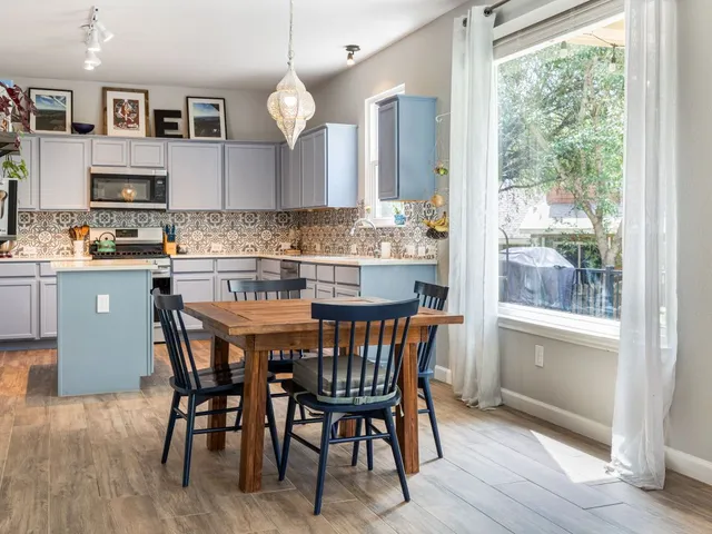 a kitchen with a dining table chairs and wooden floor