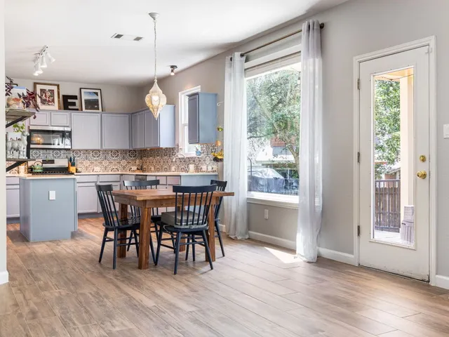 a open kitchen with stainless steel appliances granite countertop a stove a refrigerator a sink a dining table and chairs with wooden floor