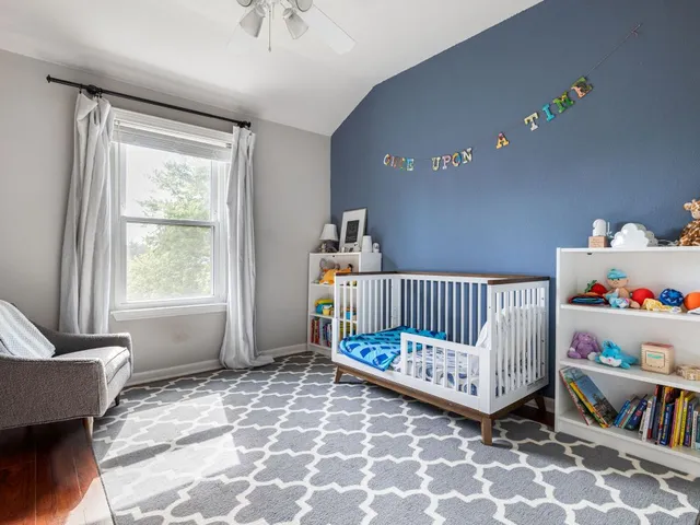 a bedroom with baby crib and a window