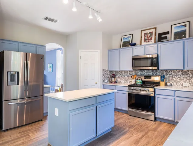 a kitchen with granite countertop a refrigerator and a stove top oven