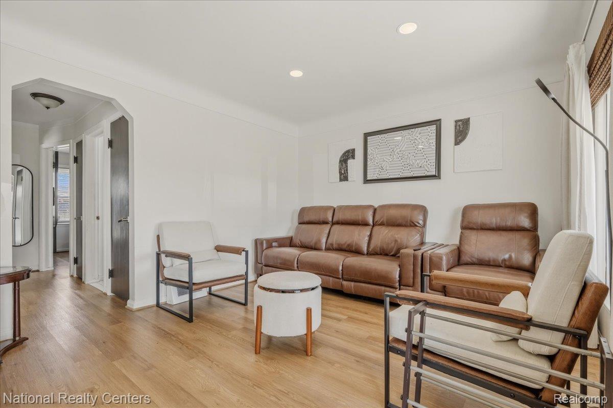Living room featuring arched walkways, light wood-style floors, and recessed lighting