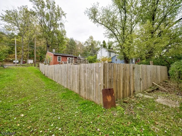 a view of backyard with wooden fence and a large tree