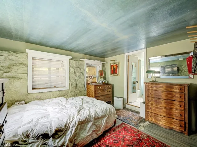 a bedroom with a bed and dresser with wooden floor