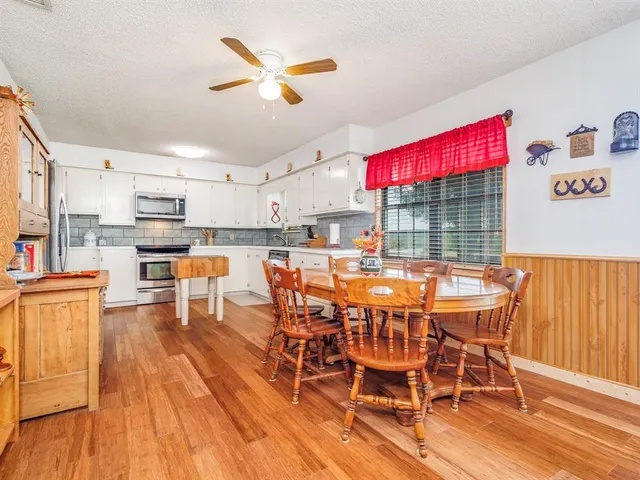 a dining area with stainless steel appliances kitchen island granite countertop a dining table chairs and sink