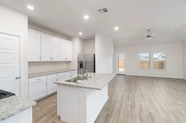 a kitchen with kitchen island sink refrigerator and cabinets