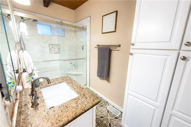 a bathroom with a granite countertop sink a mirror and shower