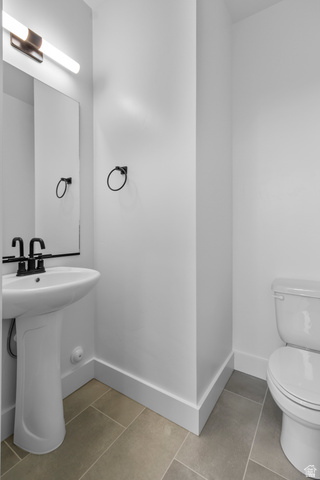 248 West 2920th Street South Logan, UT 84321 - Photo 24 of 47 Pedestal sink with a black-finish faucet, rectangular wall mirror, modern lighting fixture, and neutral-toned floor tiling