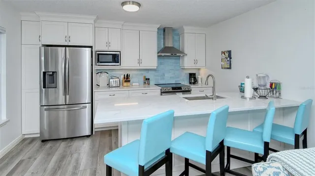 a kitchen with stainless steel appliances a refrigerator a stove a sink dishwasher and white cabinets with wooden floor