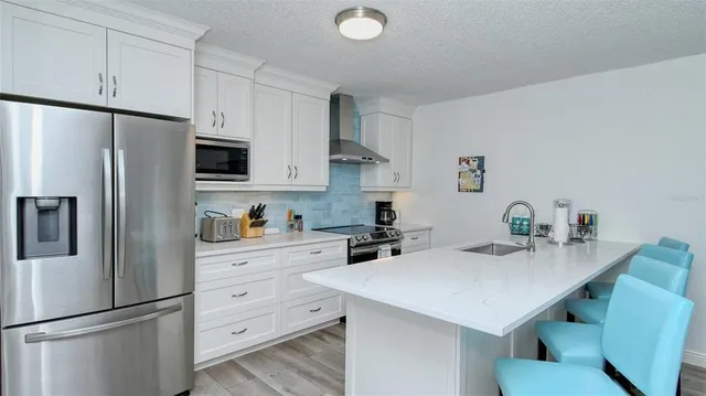 a kitchen with stainless steel appliances a sink a stove a refrigerator and white cabinets