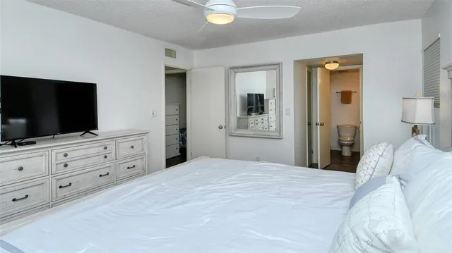 a bedroom with a bed and a flat screen tv in white walls