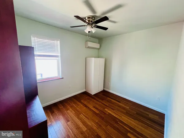 a view of an empty room with wooden floor and a ceiling fan
