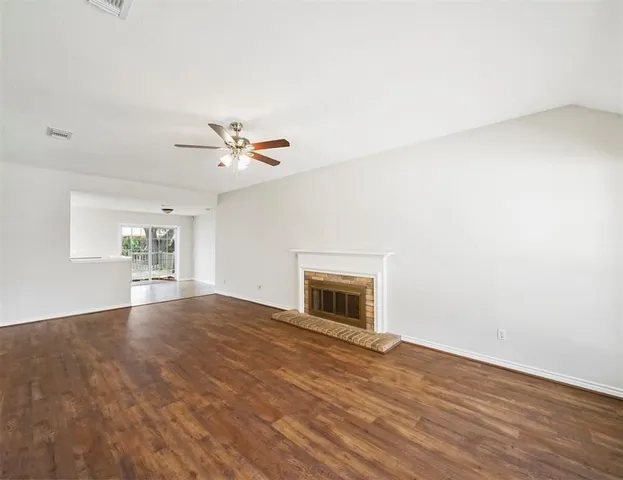 a view of an empty room with window and wooden floor